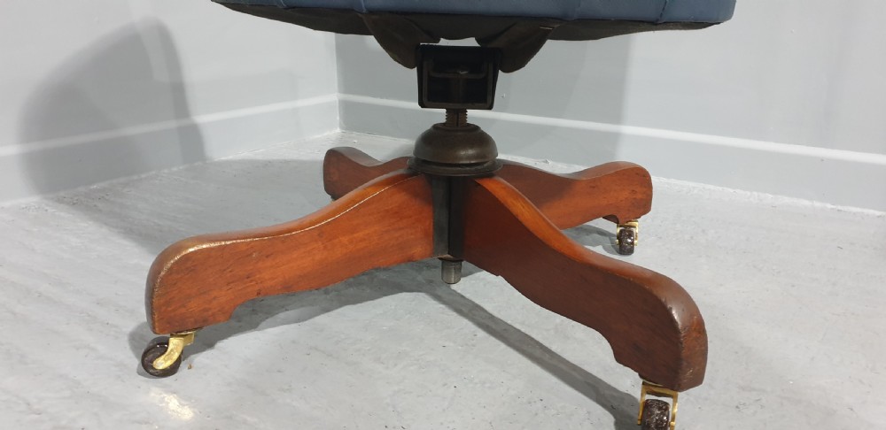 A blue leather tub desk chair with a curved backrest, brass studding detail, and a swivel wood quadruped base on castors. View VI