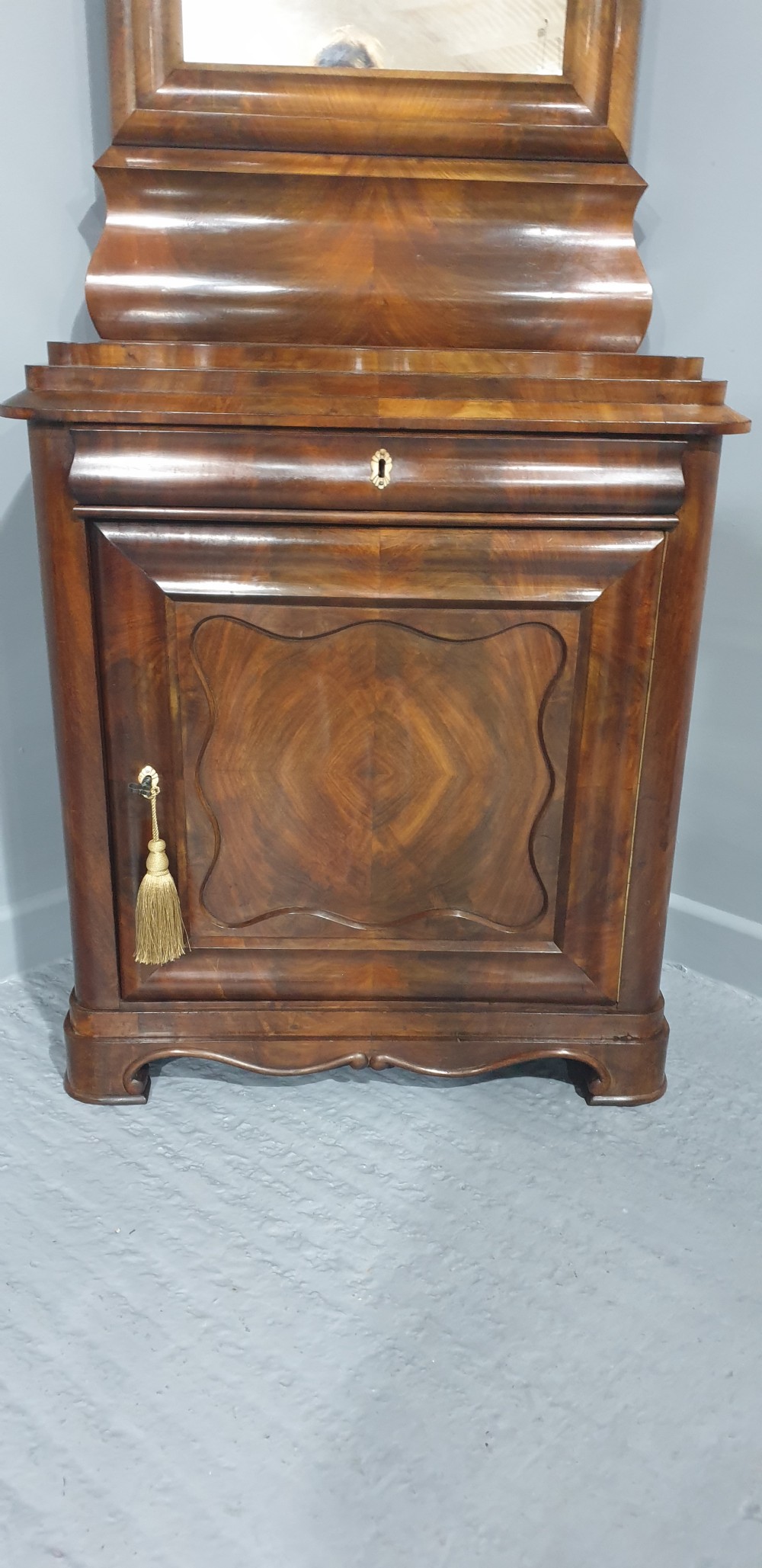 An antique Biedermeier tall warm brown veneered console cabinet featuring a fitted rectangular mirror above a single drawer and panelled cupboard base. View V