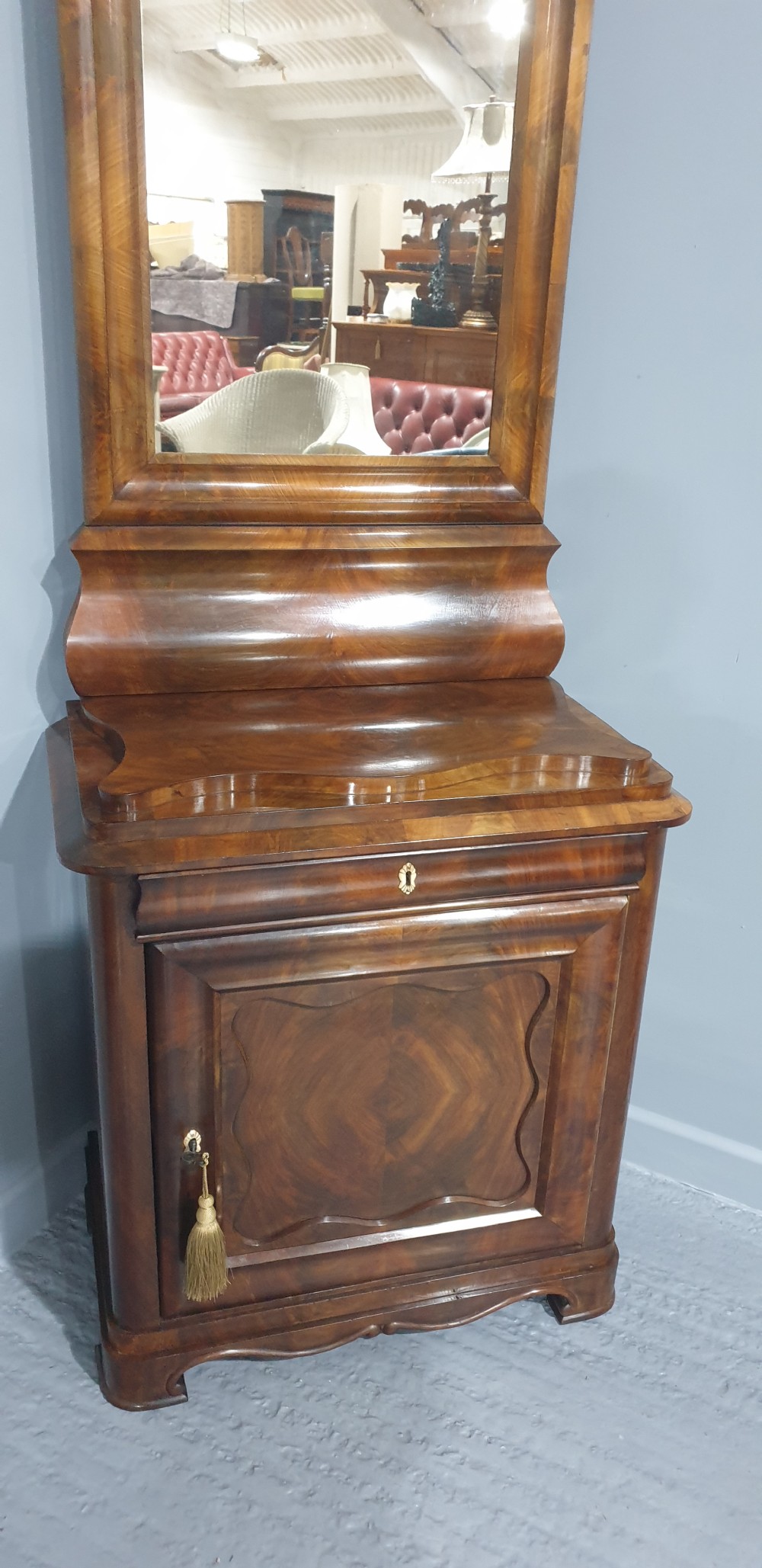 An antique Biedermeier tall warm brown veneered console cabinet featuring a fitted rectangular mirror above a single drawer and panelled cupboard base. View IX