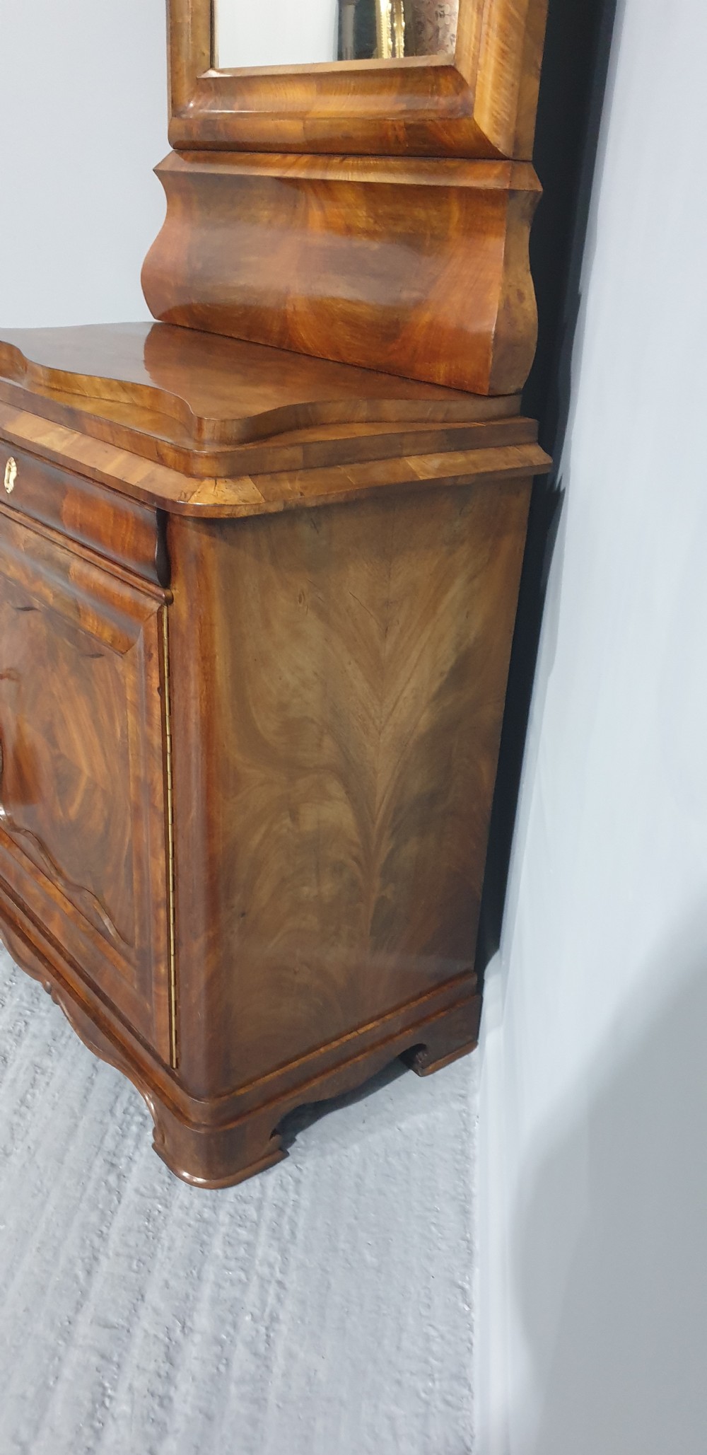 An antique Biedermeier tall warm brown veneered console cabinet featuring a fitted rectangular mirror above a single drawer and panelled cupboard base. View XII