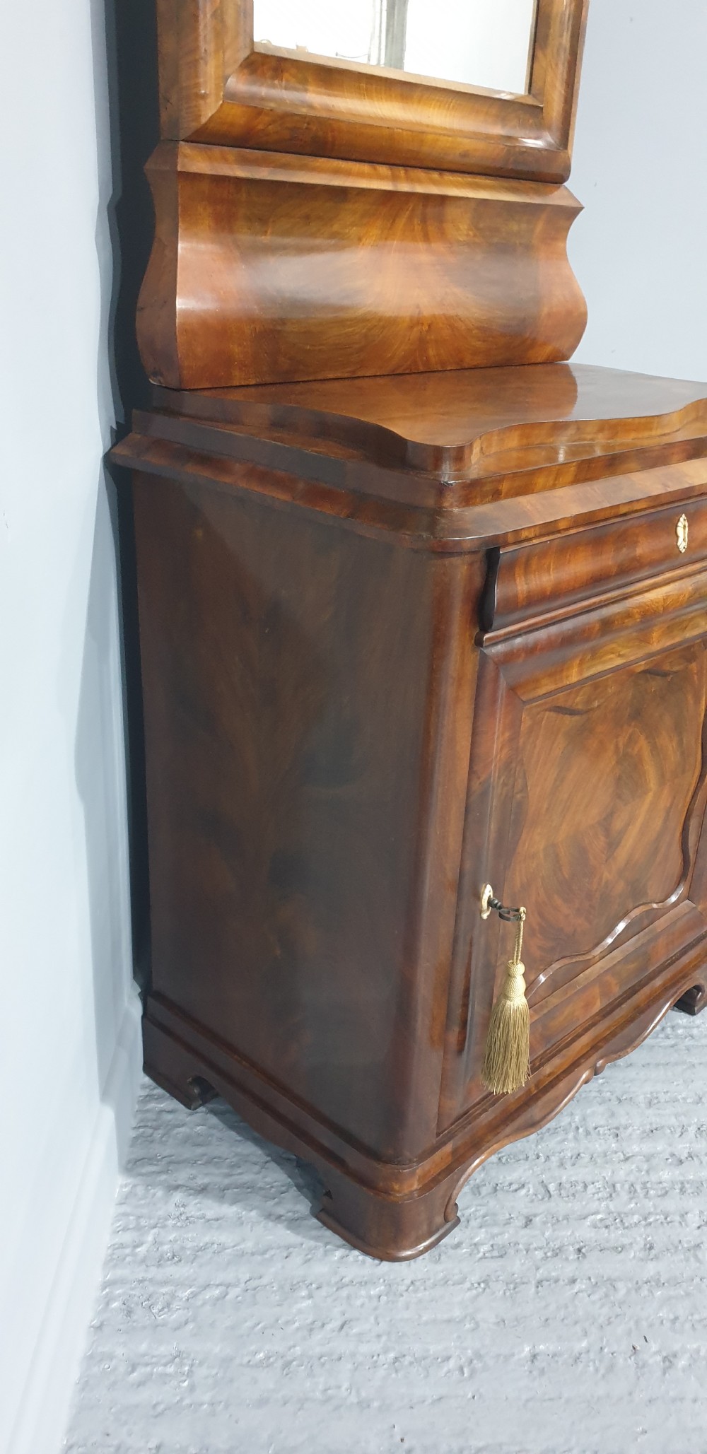 An antique Biedermeier tall warm brown veneered console cabinet featuring a fitted rectangular mirror above a single drawer and panelled cupboard base. View XIII