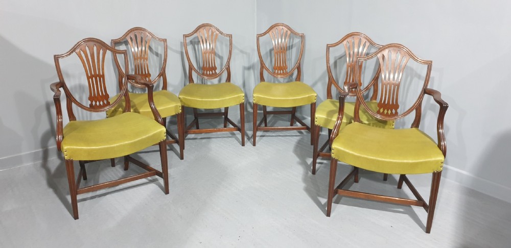 A set of six Georgian mahogany shield-back dining chairs, including two carvers and four side chairs, featuring yellow-green leather seats with brass studding. View II