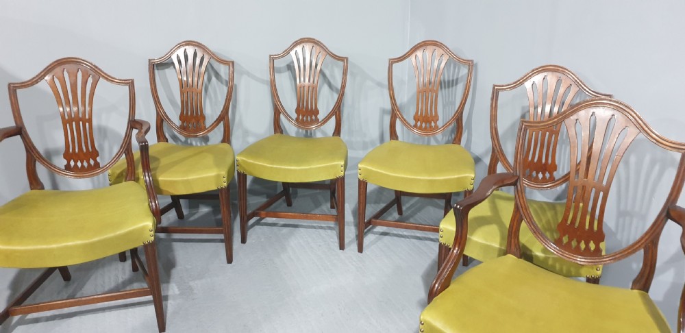 A set of six Georgian mahogany shield-back dining chairs, including two carvers and four side chairs, featuring yellow-green leather seats with brass studding. View IV