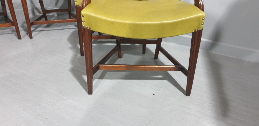 A set of six Georgian mahogany shield-back dining chairs, including two carvers and four side chairs, featuring yellow-green leather seats with brass studding. View VIII
