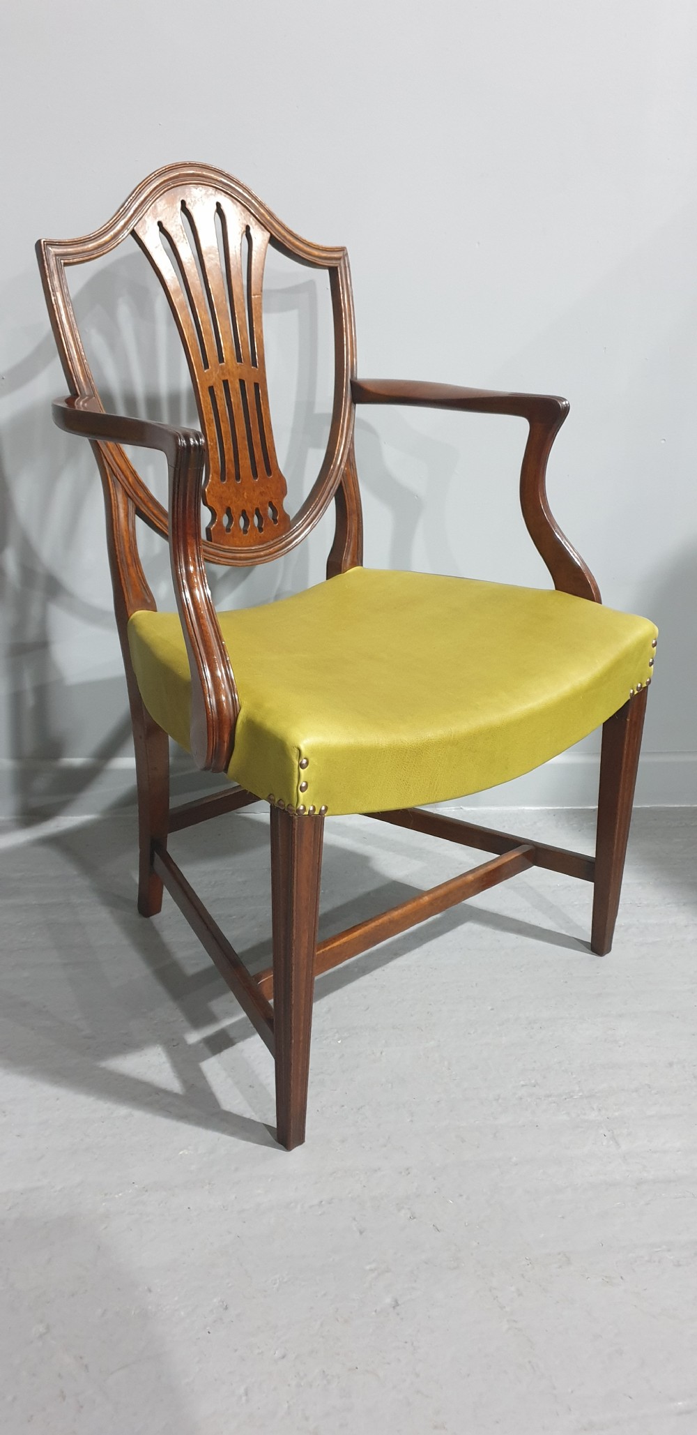 A set of six Georgian mahogany shield-back dining chairs, including two carvers and four side chairs, featuring yellow-green leather seats with brass studding. View IX