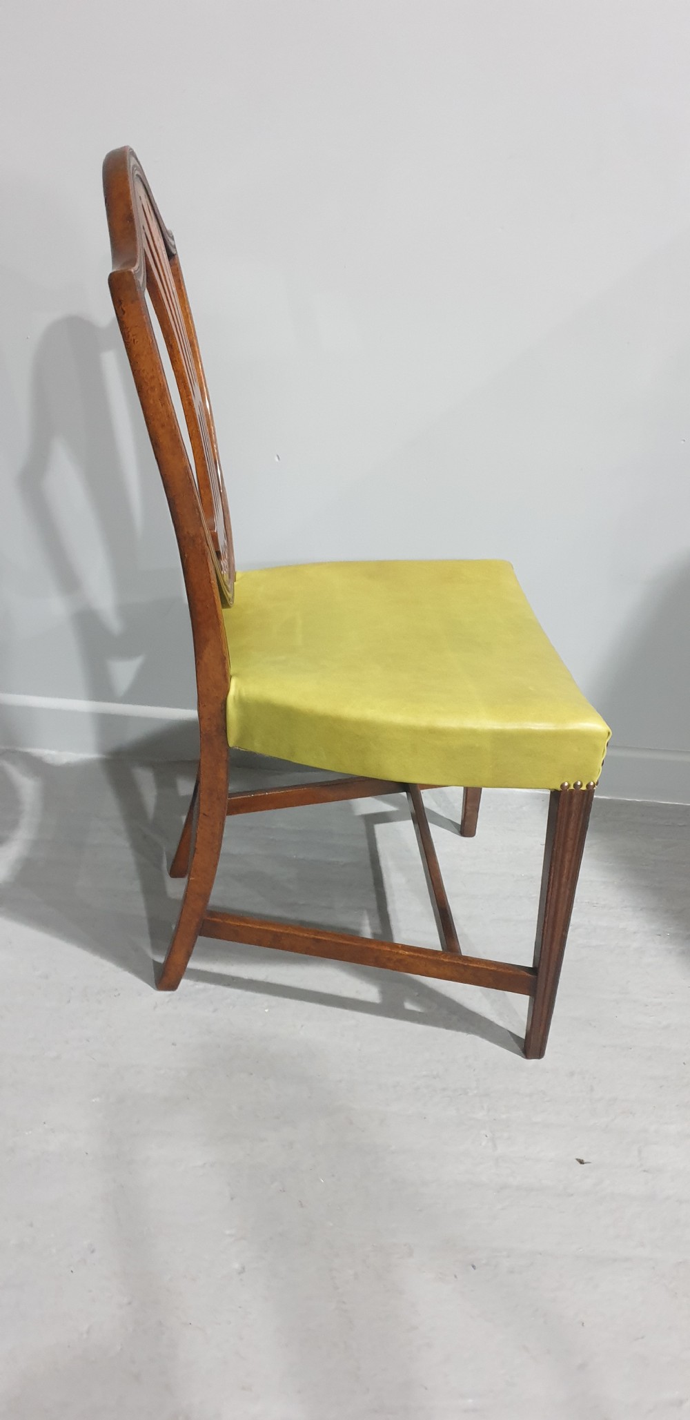 A set of six Georgian mahogany shield-back dining chairs, including two carvers and four side chairs, featuring yellow-green leather seats with brass studding. View XI