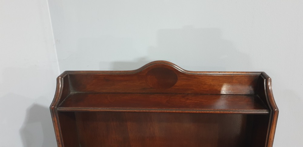 A tall, narrow mahogany cabinet featuring three open graduated shelves above a single drawer and a lower cupboard door with an oval flame mahogany inlay. View VII