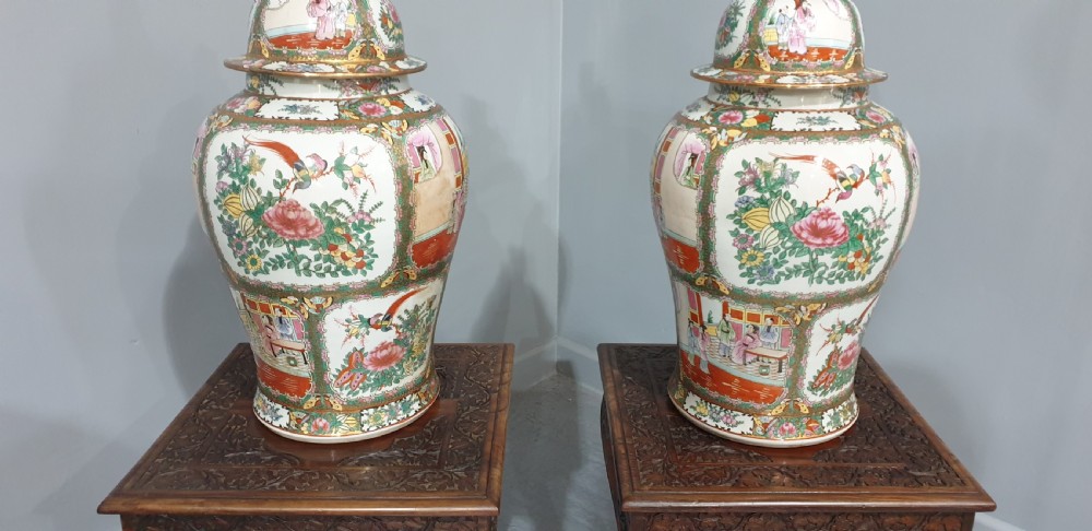 A pair of carved dark padouk wood low tables supporting large Cantonese famille rose porcelain temple jars topped with sculpted lion finials. View II