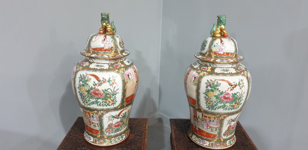 A pair of carved dark padouk wood low tables supporting large Cantonese famille rose porcelain temple jars topped with sculpted lion finials. View III