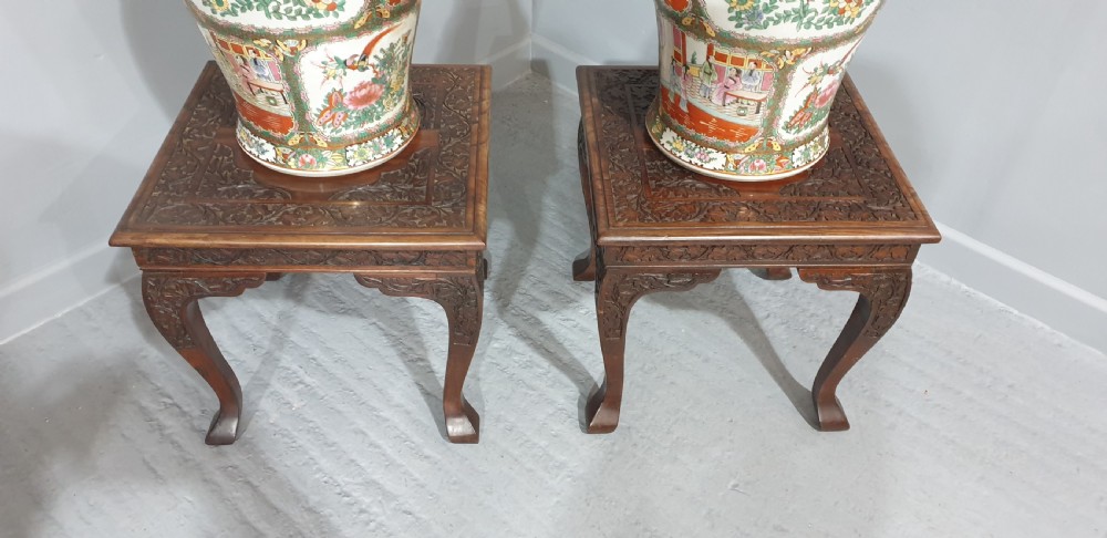 A pair of carved dark padouk wood low tables supporting large Cantonese famille rose porcelain temple jars topped with sculpted lion finials. View VI