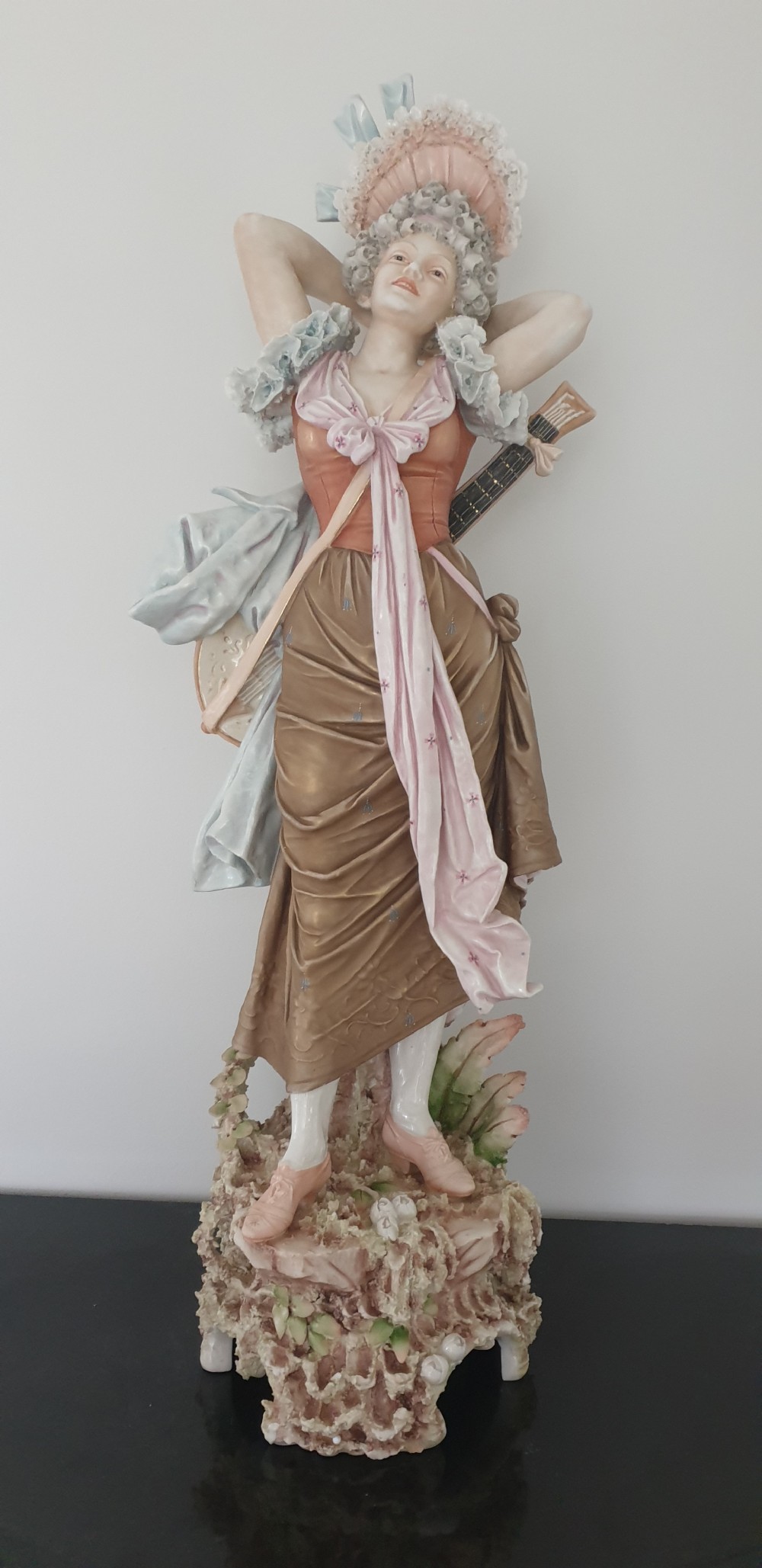 A tall Royal Dux porcelain figure of a lady in historical attire holding a musical instrument on an ornate base. View V