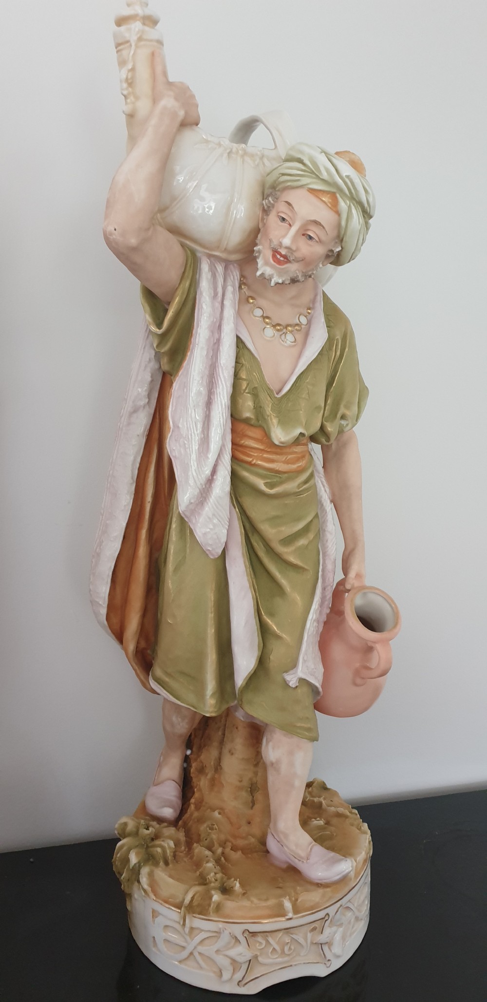 A pair of large antique Royal Dux porcelain figures depicting male and female water carriers in olive green and terracotta attire. View II