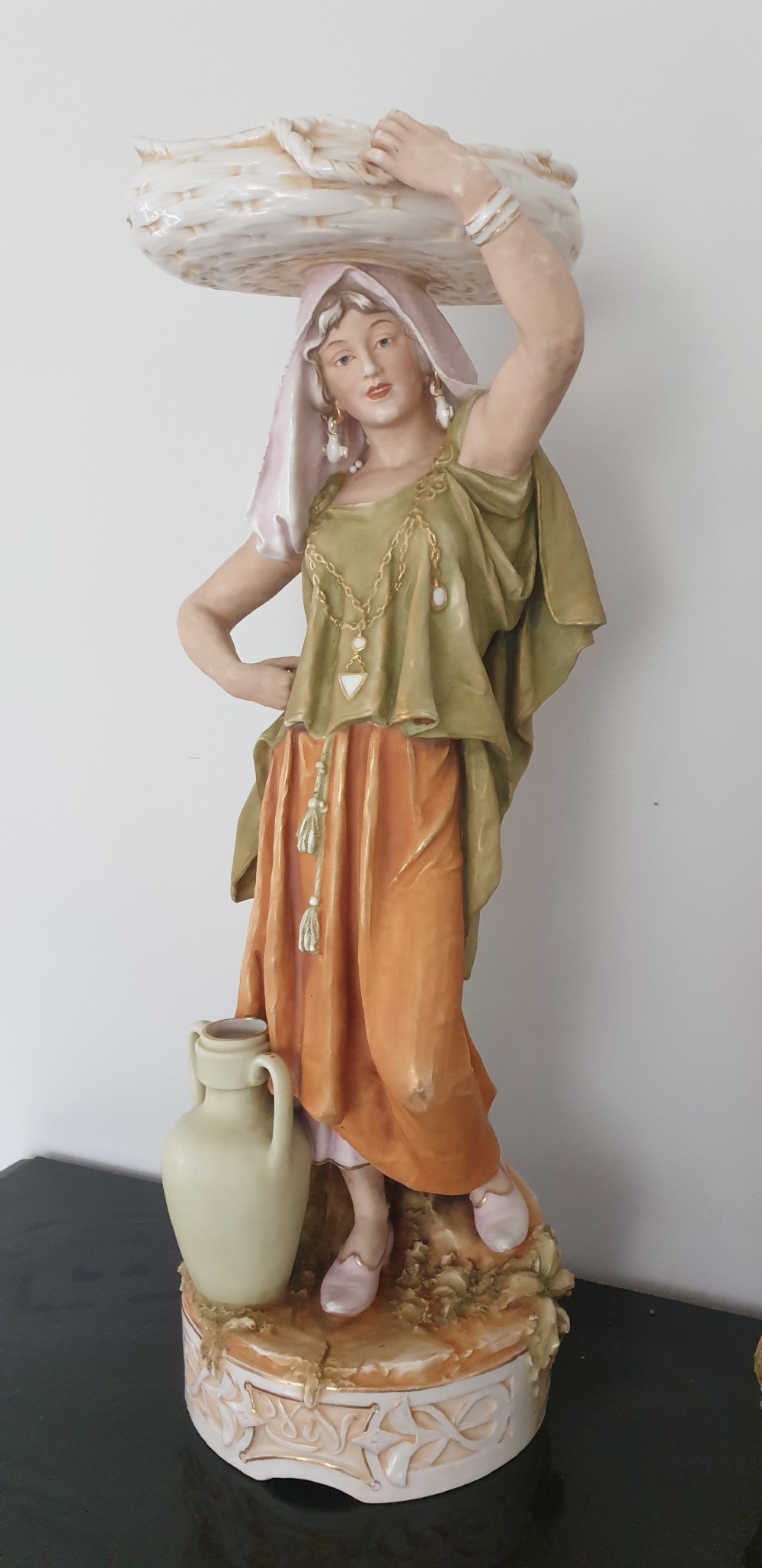 A pair of large antique Royal Dux porcelain figures depicting male and female water carriers in olive green and terracotta attire. View IV