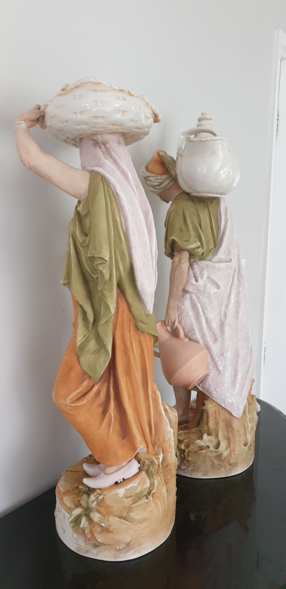 A pair of large antique Royal Dux porcelain figures depicting male and female water carriers in olive green and terracotta attire. View VIII
