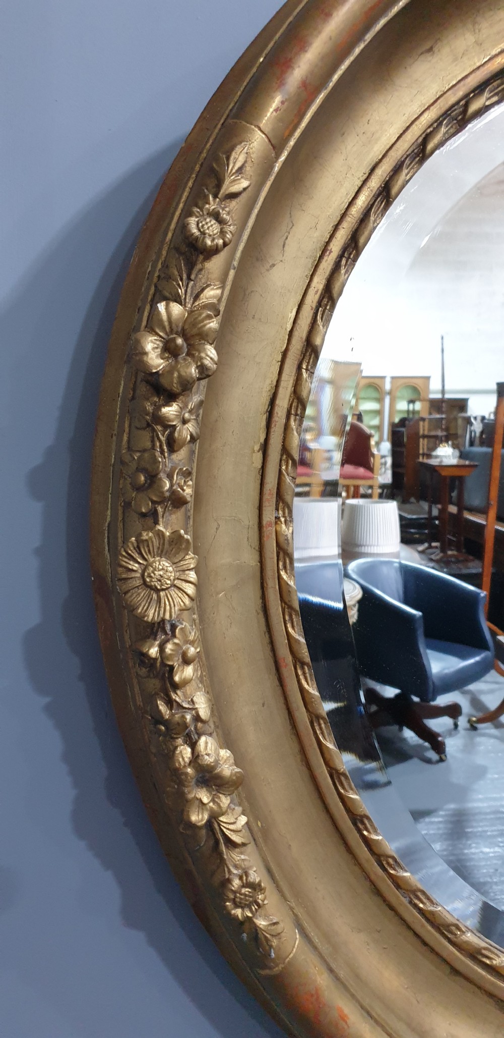An oval Victorian wall mirror featuring a giltwood frame decorated with a floral motif outer border and a inner rope twist moulding. View III