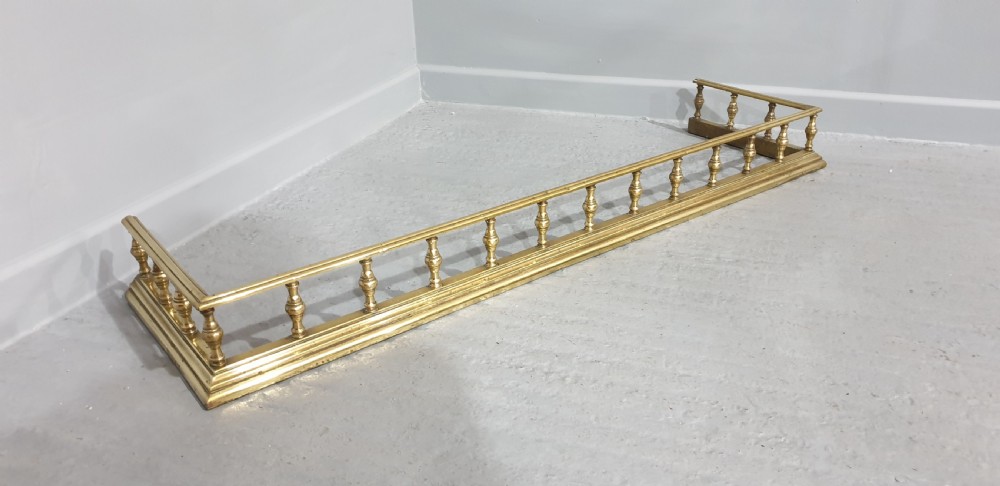 A low Regency style polished brass fireplace fender featuring turned baluster spindles along a moulded base. View III
