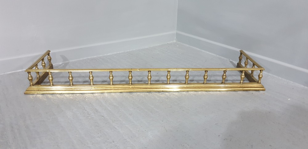 A low Regency style polished brass fireplace fender featuring turned baluster spindles along a moulded base. View V