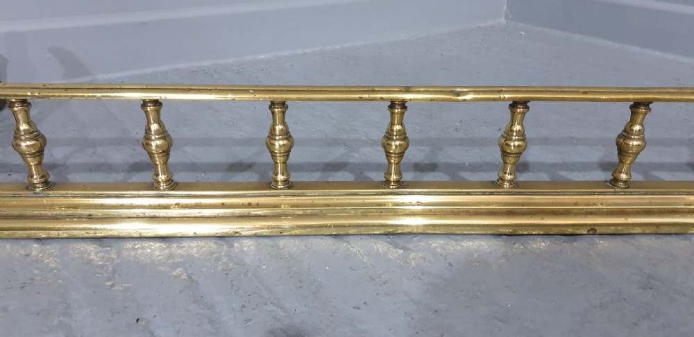 A low Regency style polished brass fireplace fender featuring turned baluster spindles along a moulded base. View VI