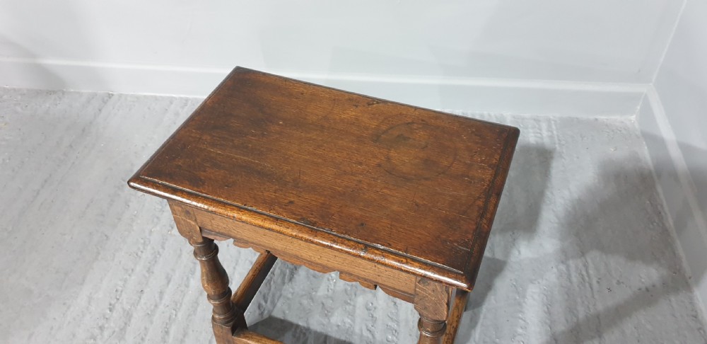A rectangular oak joint stool featuring turned legs, a shaped apron, and perimeter box stretchers. View IV