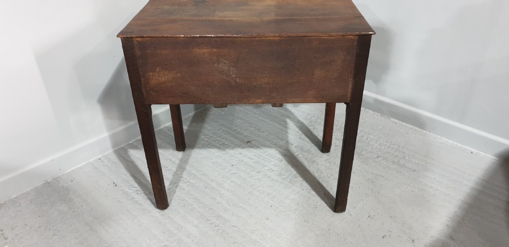 A Georgian oak lowboy featuring three drawers with brass handles, a central carved fretwork apron, and straight square legs. View VIII