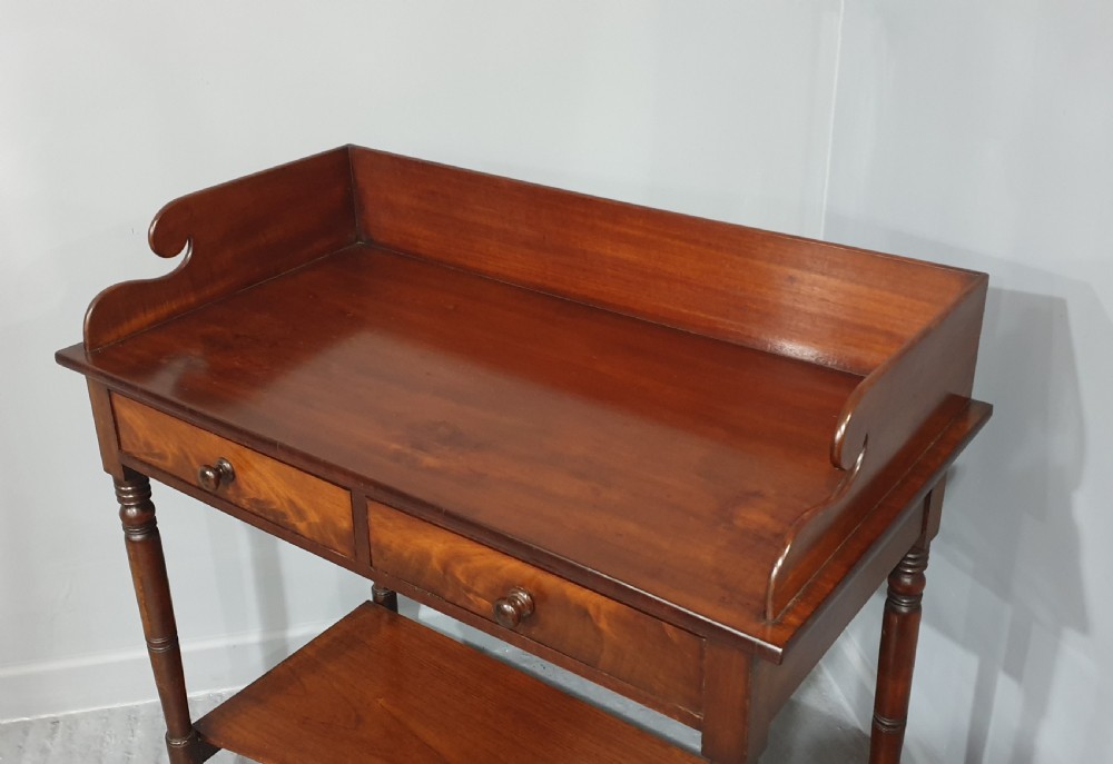 An antique mahogany side table featuring a raised gallery splashback, two frieze drawers with wooden knobs, turned legs, and a lower curved shelf. View IV