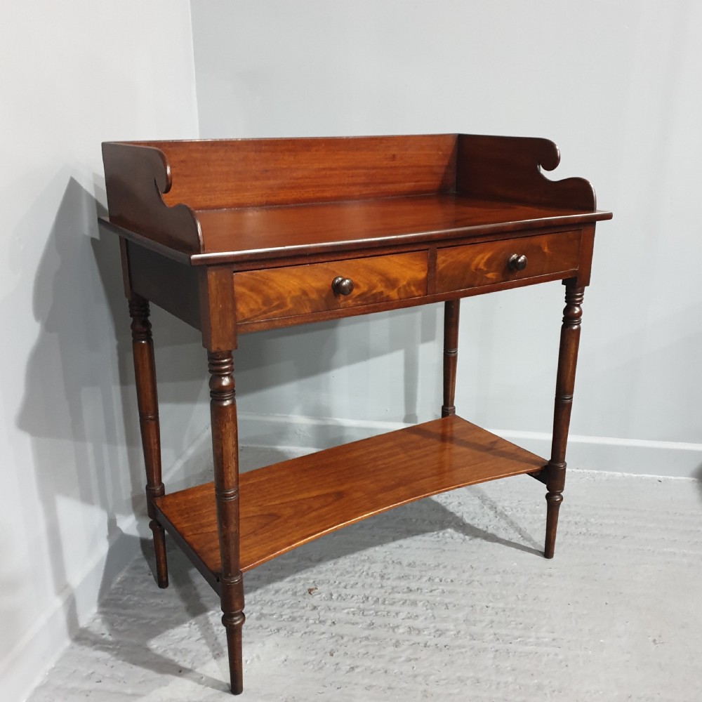 An antique mahogany side table featuring a raised gallery splashback, two frieze drawers with wooden knobs, turned legs, and a lower curved shelf. View VII