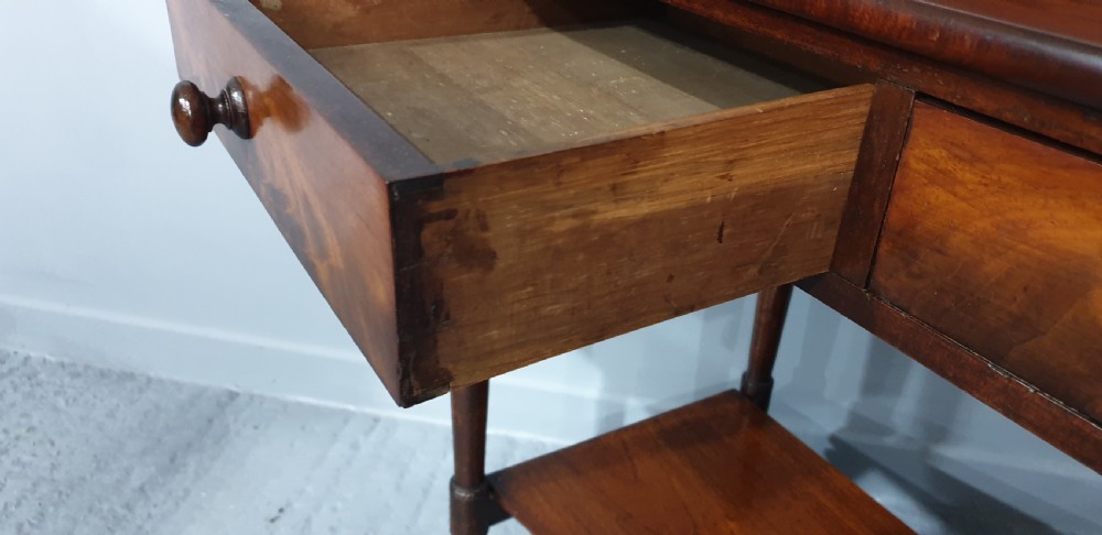 An antique mahogany side table featuring a raised gallery splashback, two frieze drawers with wooden knobs, turned legs, and a lower curved shelf. View VIII