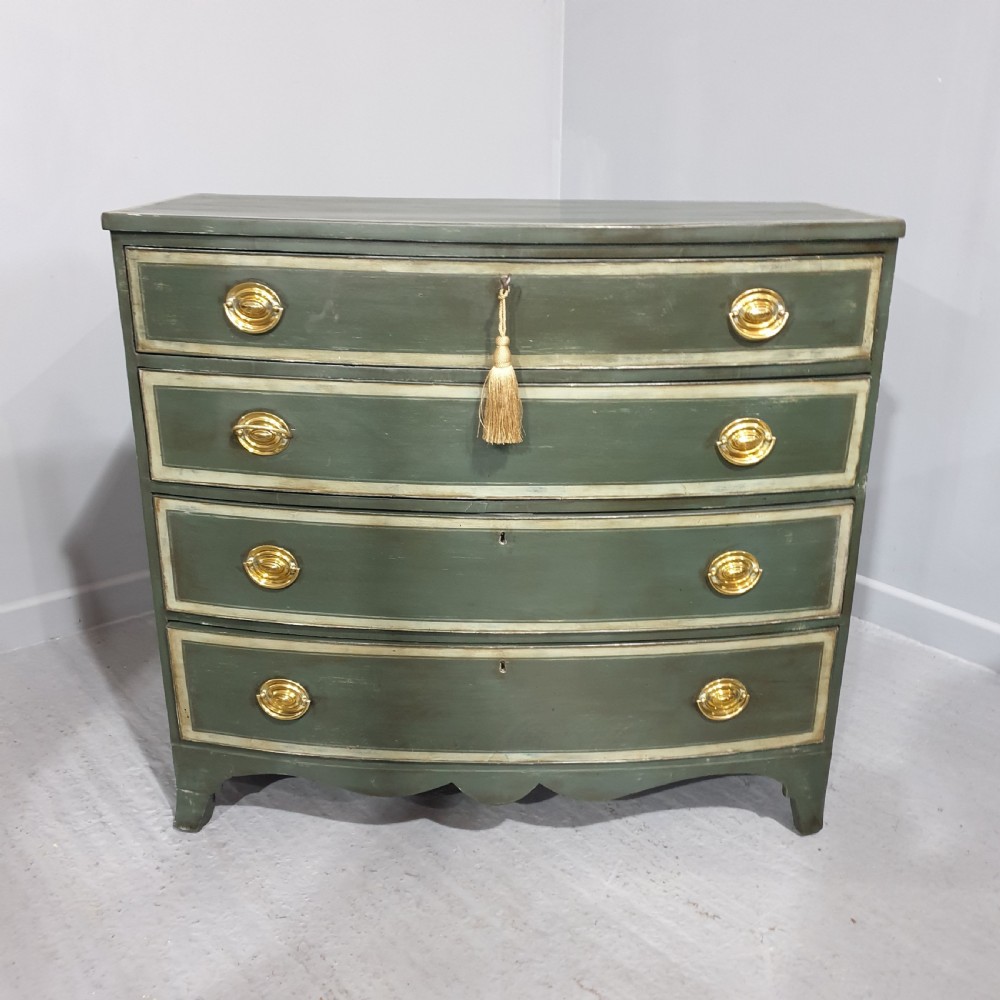 A Georgian green painted bowfront chest of drawers featuring four graduated drawers with cream painted border lines and brass oval drop handles.