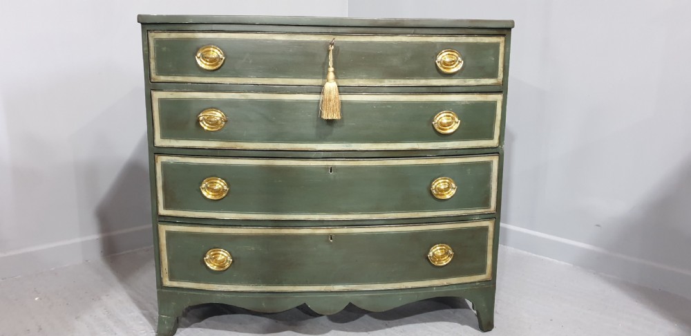 A Georgian green painted bowfront chest of drawers featuring four graduated drawers with cream painted border lines and brass oval drop handles. View II