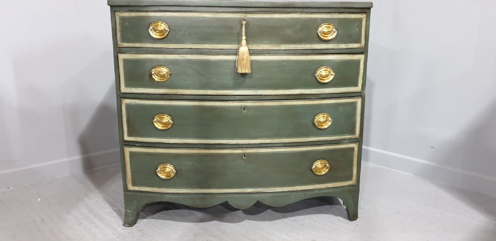 A Georgian green painted bowfront chest of drawers featuring four graduated drawers with cream painted border lines and brass oval drop handles. View III