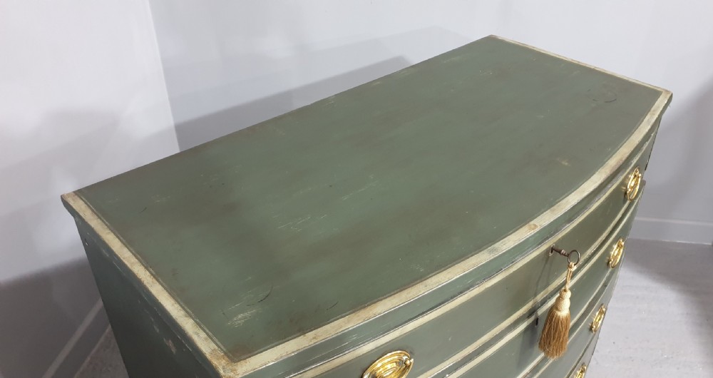 A Georgian green painted bowfront chest of drawers featuring four graduated drawers with cream painted border lines and brass oval drop handles. View VII