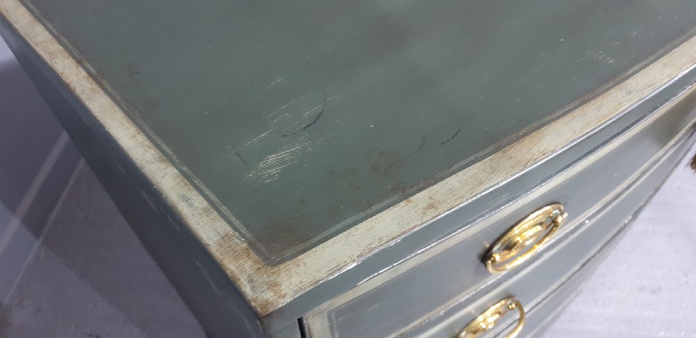 A Georgian green painted bowfront chest of drawers featuring four graduated drawers with cream painted border lines and brass oval drop handles. View VIII