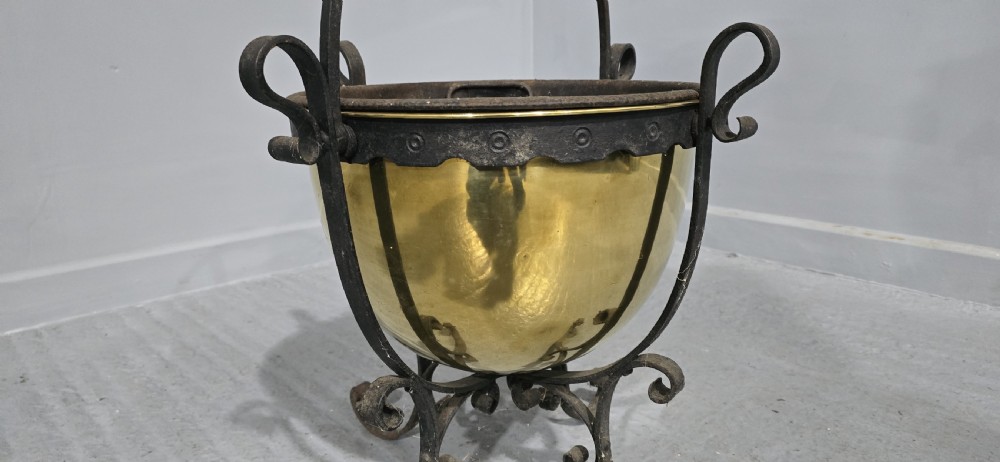 An Arts and Crafts coal bucket featuring a hemispherical brass bowl set within a wrought iron frame with scrolled feet and a spiral wire handle. View V