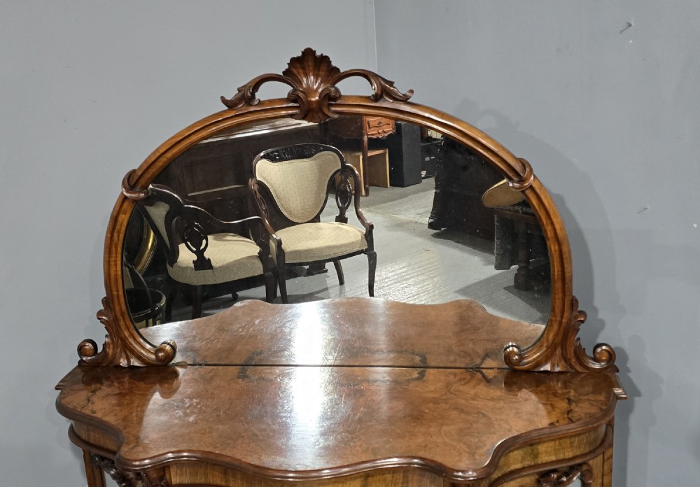 An antique burr walnut side cabinet featuring an arched top mirror with a carved cresting and glass mirrored door panels. View VII