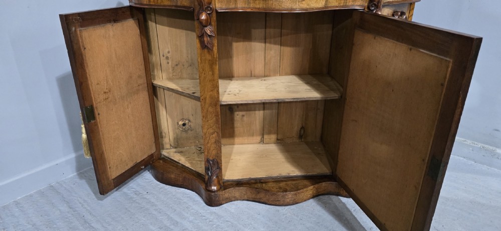 An antique burr walnut side cabinet featuring an arched top mirror with a carved cresting and glass mirrored door panels. View VIII