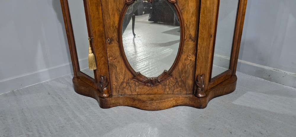 An antique burr walnut side cabinet featuring an arched top mirror with a carved cresting and glass mirrored door panels. View XII