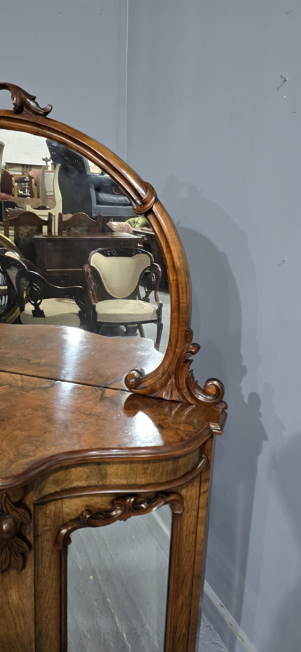 An antique burr walnut side cabinet featuring an arched top mirror with a carved cresting and glass mirrored door panels. View XIV