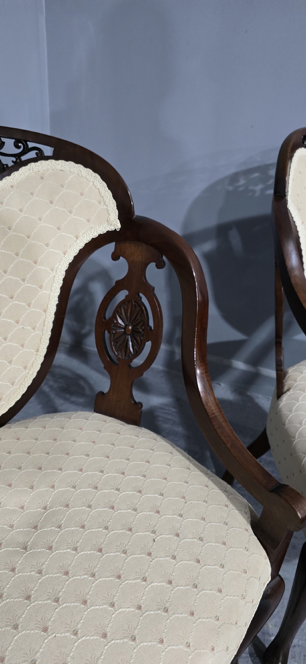 A pair of antique Victorian mahogany elbow chairs featuring carved crest rails, pierced arm supports, cabriole legs, and cream upholstered seats. View IV
