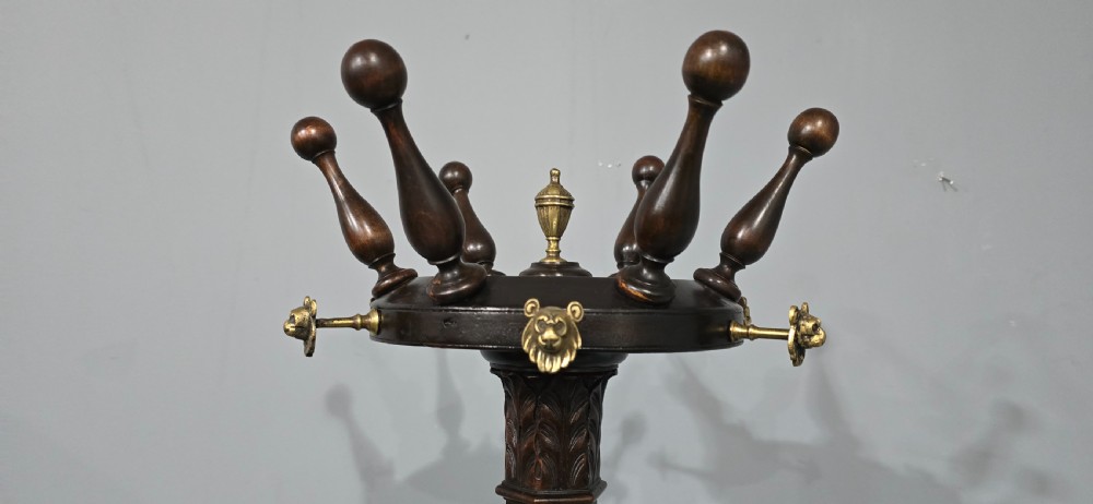 A tall dark mahogany freestanding coat stand featuring turned wooden pegs, brass accents, a fluted column, and a curved tripod base. View III