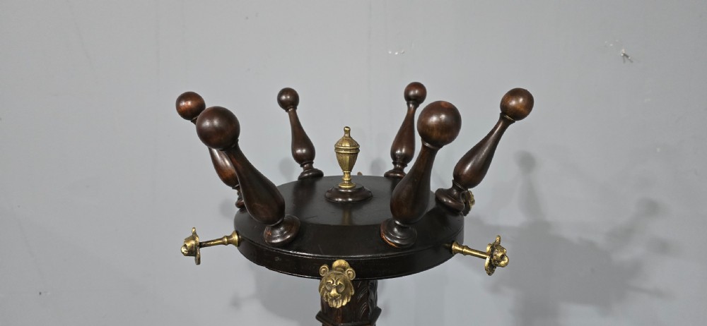 A tall dark mahogany freestanding coat stand featuring turned wooden pegs, brass accents, a fluted column, and a curved tripod base. View V