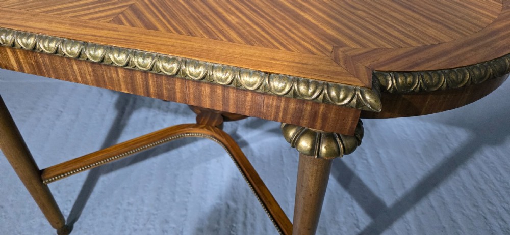 An oval satinwood coffee table featuring a parquetry top, gilt egg-and-dart rim moulding, fluted tapered legs, and an X-frame stretcher. View III