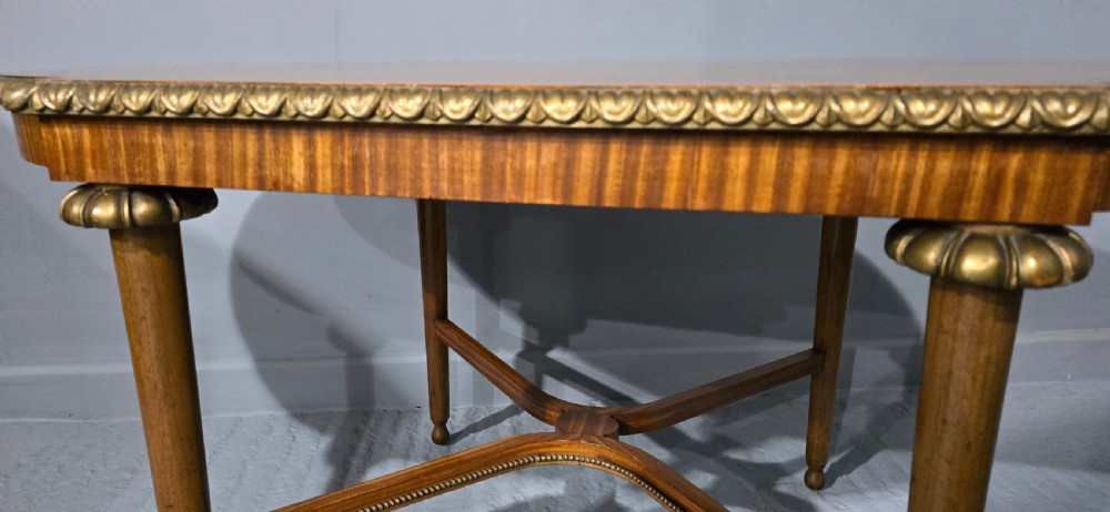 An oval satinwood coffee table featuring a parquetry top, gilt egg-and-dart rim moulding, fluted tapered legs, and an X-frame stretcher. View VII
