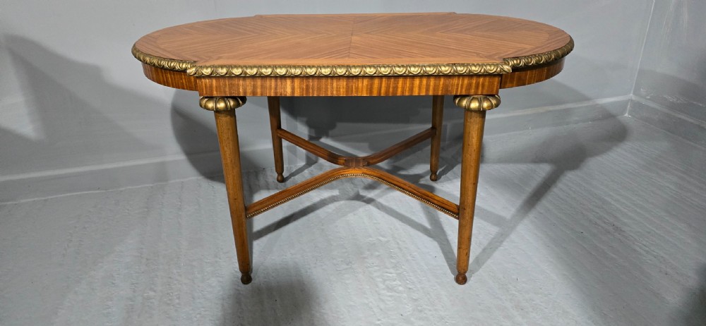An oval satinwood coffee table featuring a parquetry top, gilt egg-and-dart rim moulding, fluted tapered legs, and an X-frame stretcher. View VIII