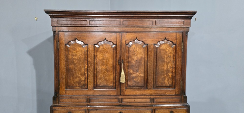 A tall Georgian oak and elm livery cupboard featuring arched panelled doors above multiple drawers with turned wooden knobs. View II