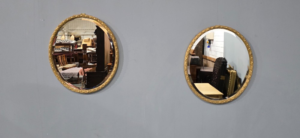 A pair of matching oval wall mirrors featuring molded gold gilt frames and bevelled glass plates. View III
