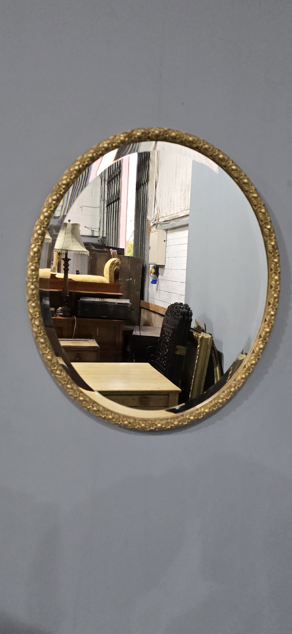 A pair of matching oval wall mirrors featuring molded gold gilt frames and bevelled glass plates. View IV