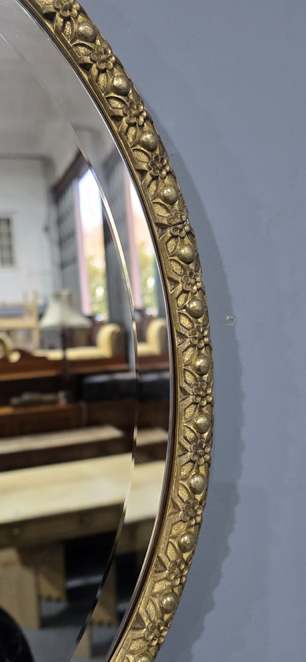 A pair of matching oval wall mirrors featuring molded gold gilt frames and bevelled glass plates. View V