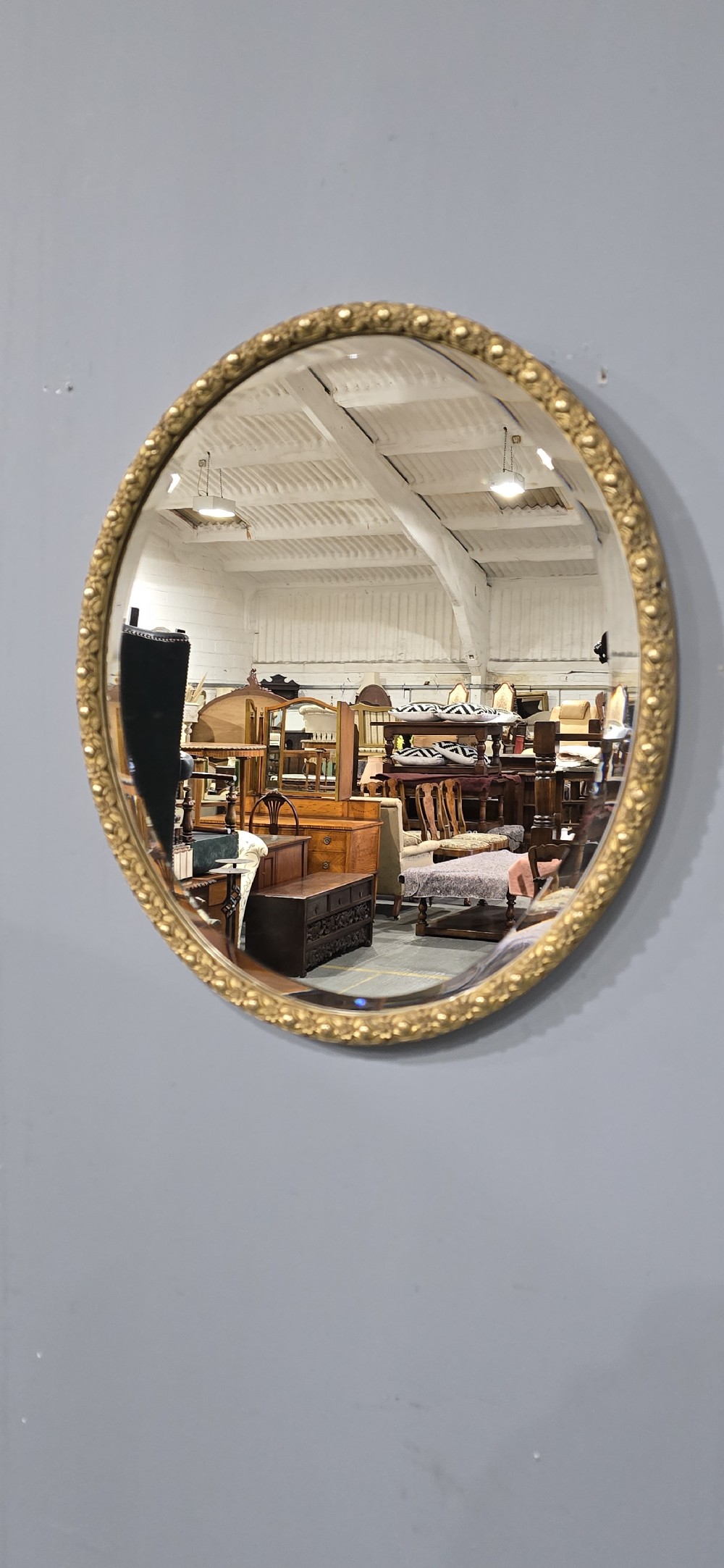 A pair of matching oval wall mirrors featuring molded gold gilt frames and bevelled glass plates. View VI