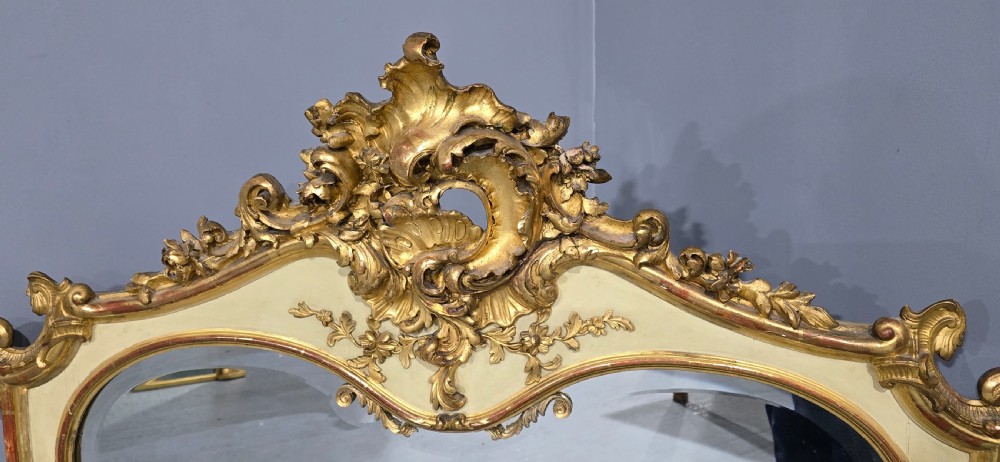 A large Victorian Rococo Revival giltwood and cream painted overmantel mirror featuring shell cresting, carved scrolls, and an arched glass plate. View III
