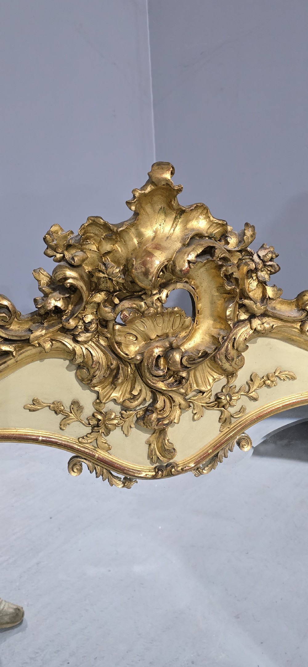 A large Victorian Rococo Revival giltwood and cream painted overmantel mirror featuring shell cresting, carved scrolls, and an arched glass plate. View VIII